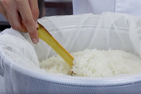 finished cooked rice in a rice cooker being fluffed with a rice paddle