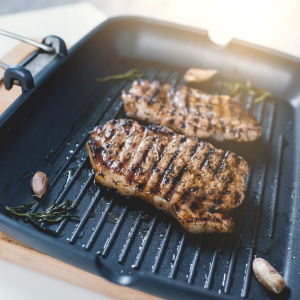 a seasoned cast iron grill pan with steaks