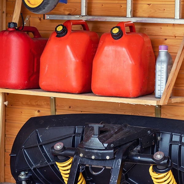 three red plastic gas cans on shelf in wooden shed