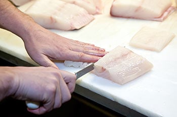 hands fileting raw fish with knife