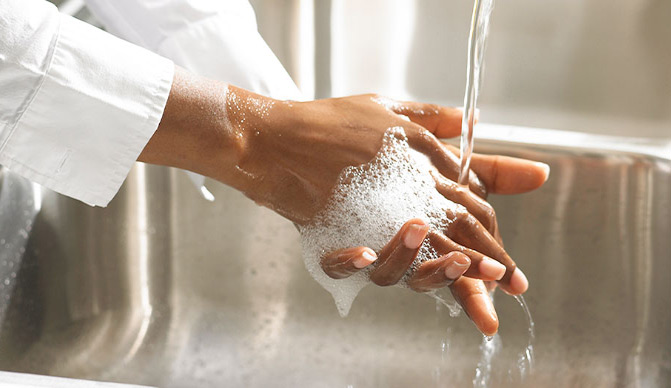 Server rubbing hands together with soap under running water