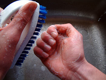 hands scrubbing nails with a nail cleaning brush