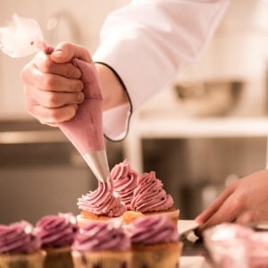 A Pastry Chef decorating a cupcake