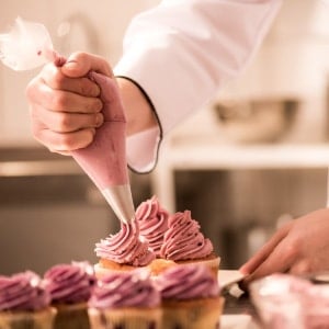 Un pastelero decorando un cupcake