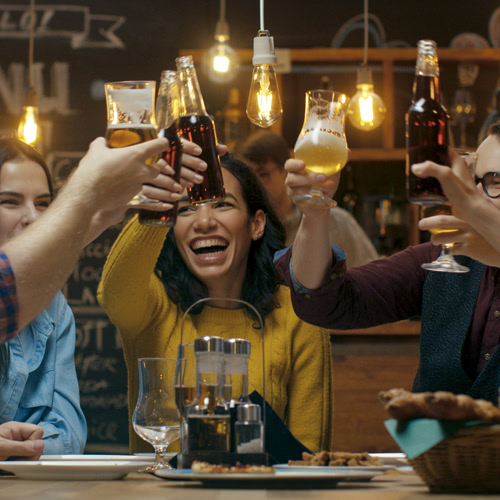 A group of smiling friends cheers at a table in a rustic bar