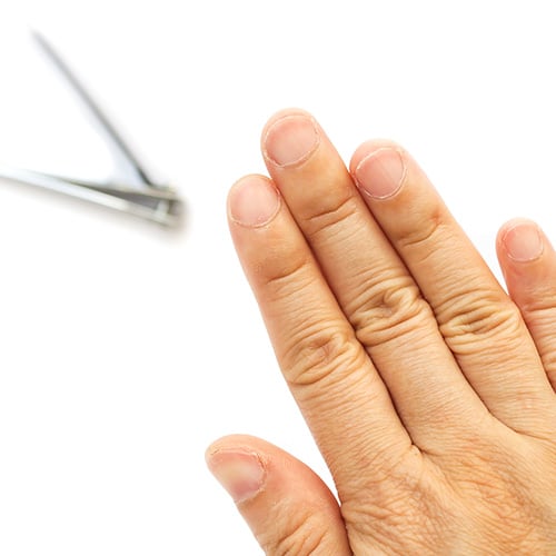 Hand showing short trimmed nails with nail clippers in the background