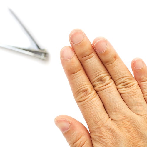 Mão mostrando unhas aparadas curtas com cortador de unhas no fundo