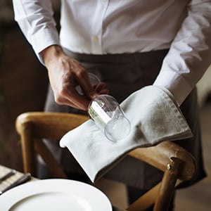 waiter cleaning a glass with a white cloth